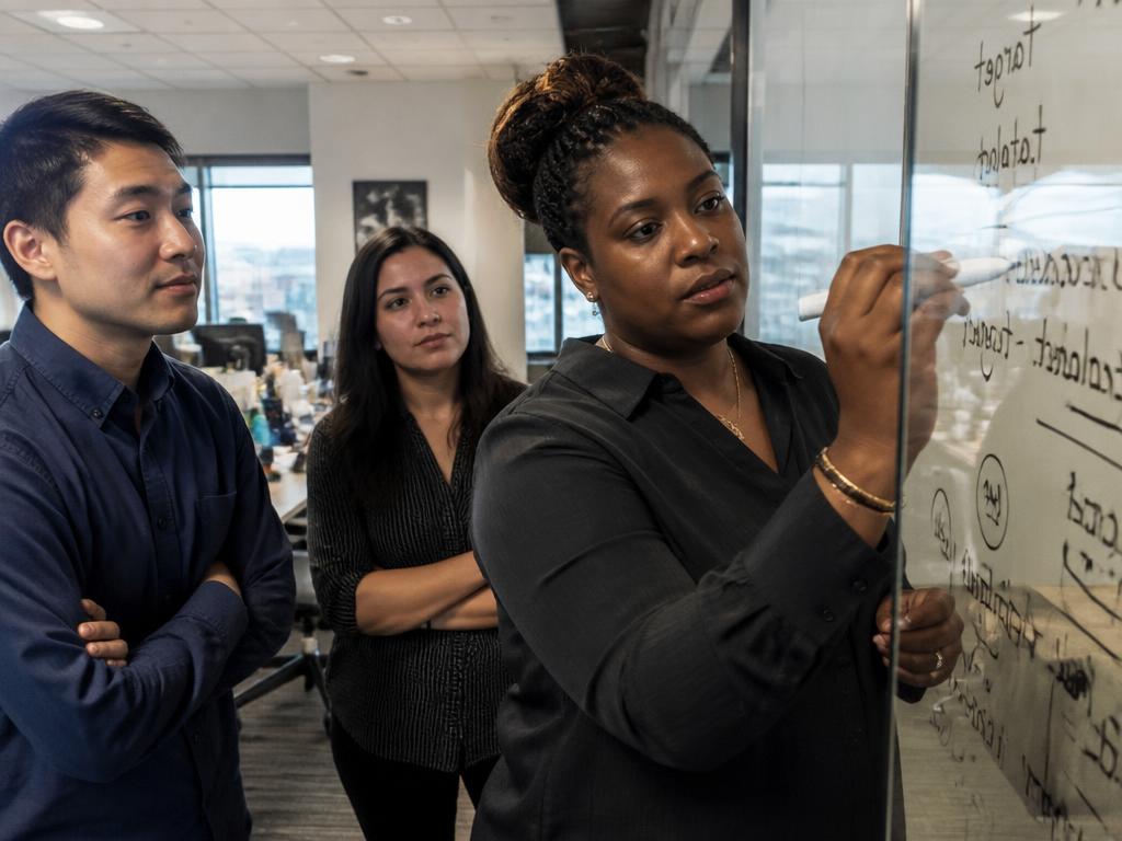 A team lead teaching a teammate at a glass whiteboard