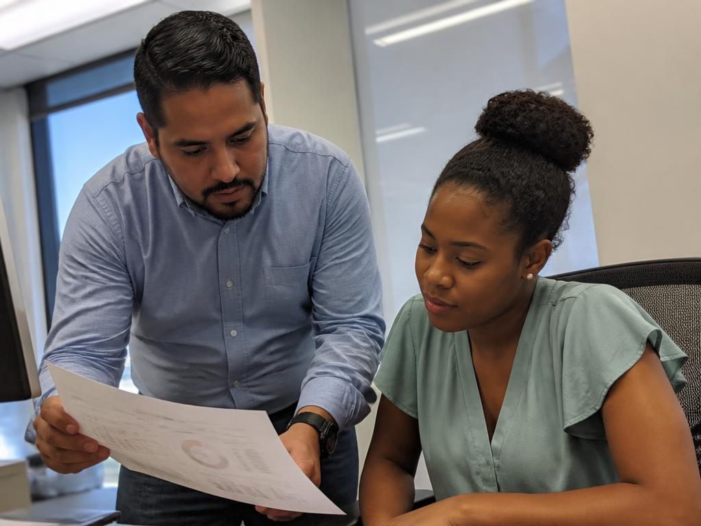 A mentor reviewing a report with a colleague at their desk